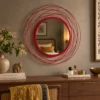 Red round wall mirror above dark wood console